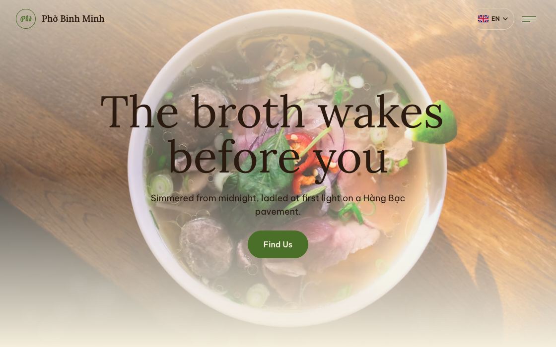 A top-down bowl of phở with rare beef, lime and fresh herbs